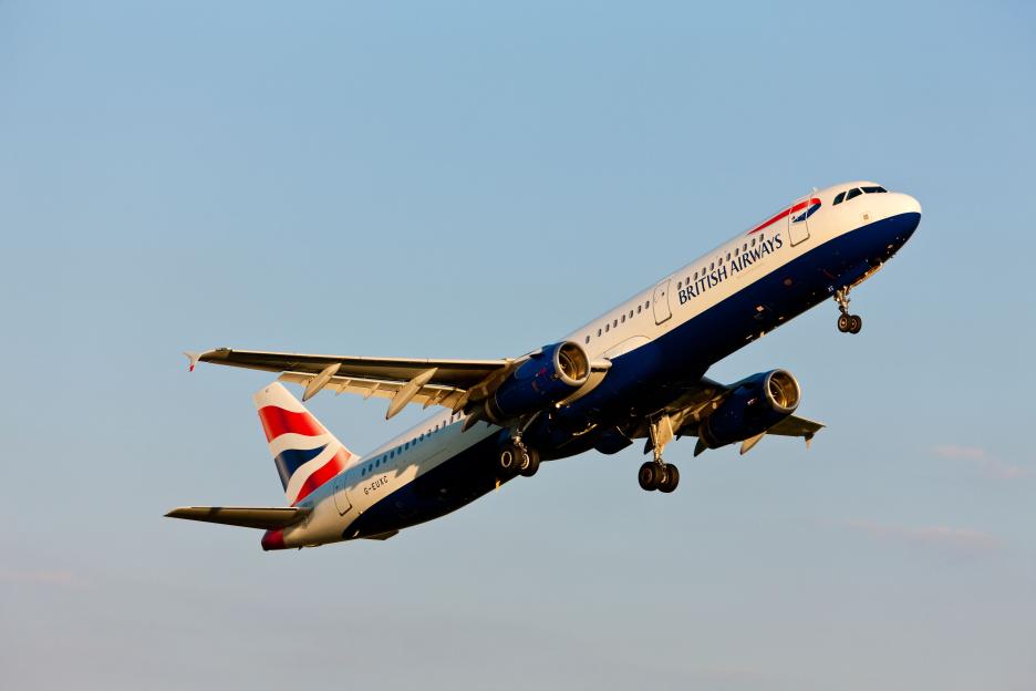 A British Airways Airbus A321 taking off with its landing gear down against a light blue sky.