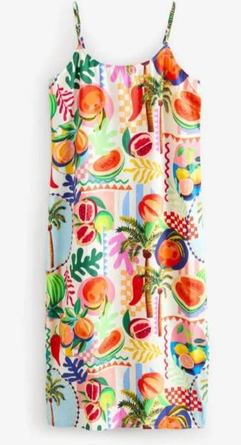 White holiday dress with a colorful fruit and palm tree pattern.