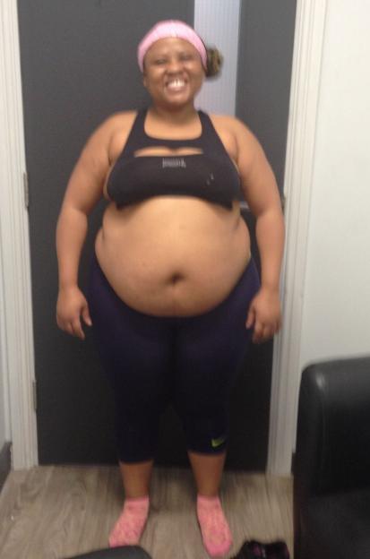 A full-body photo of Charmaine Masoeu standing, smiling, wearing a black sports bra, blue leggings, and pink socks.