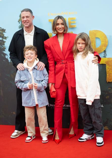 A man, woman, and two children standing on a red carpet at "The Wild Robot" Headline Gala.