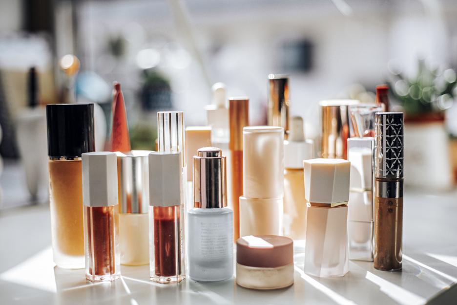 Group of skincare and cosmetic products on a table illuminated by sunlight.