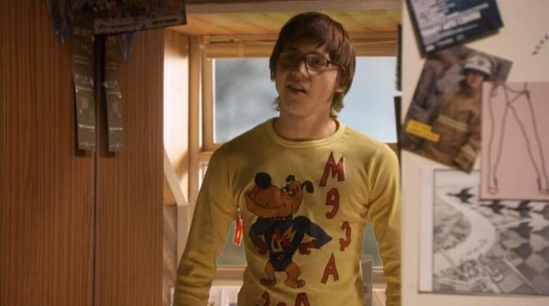 Sid Jenkins (Mike Bailey) wearing glasses and a long-sleeved yellow shirt with a dog cartoon on it.