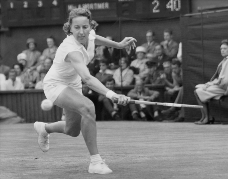 A female tennis player in action, hitting a ball with her racket on the court.