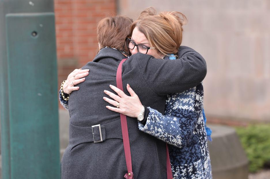 Two women embrace in an emotional hug outdoors.