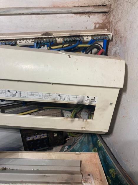 A damaged electrical fuse box showing exposed wires and labels for circuits like "lights" and "sockets."