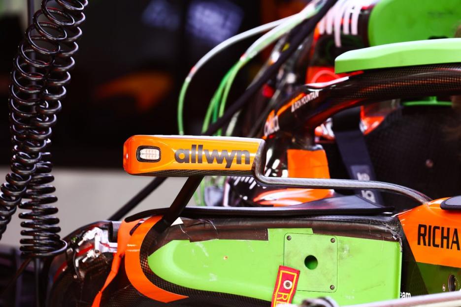 An orange "allwyn" sponsor sticker on the side of a racing car.