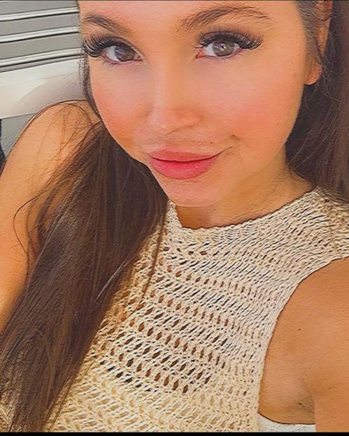 A close-up of Samantha Murphy, a woman with long dark hair, wearing a crocheted top, looking at the camera.