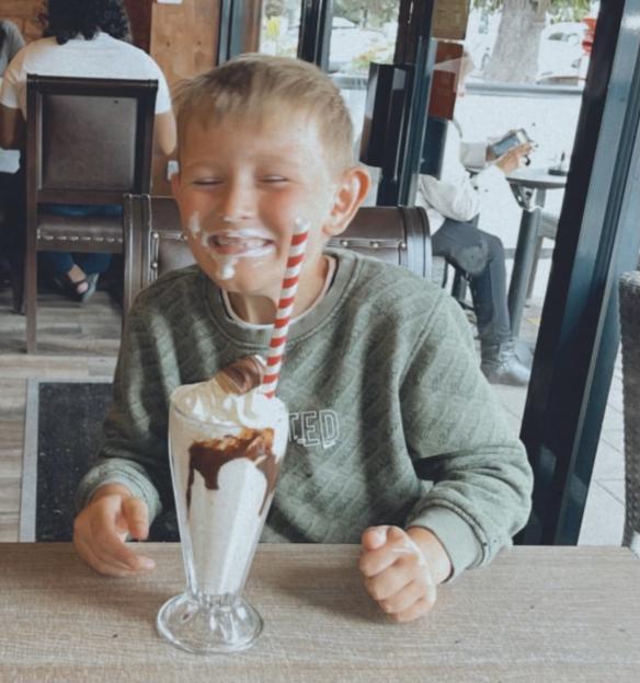 Archie Battersbee, an 11-year-old boy, with whipped cream on his face and a milkshake in front of him.