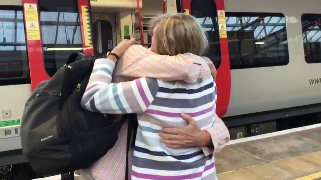 Michael Bardsley and Gill Thompson embracing at a train station.
