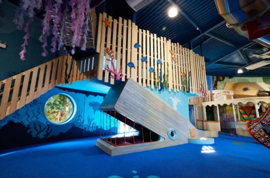 The Playhive indoor play area with ocean-themed decor, including a whale slide and a jungle cruise boat.