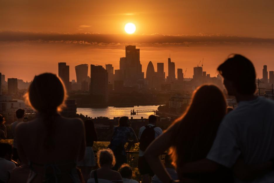Silhouetted crowd watching the sunset over London's financial district from Greenwich Park.