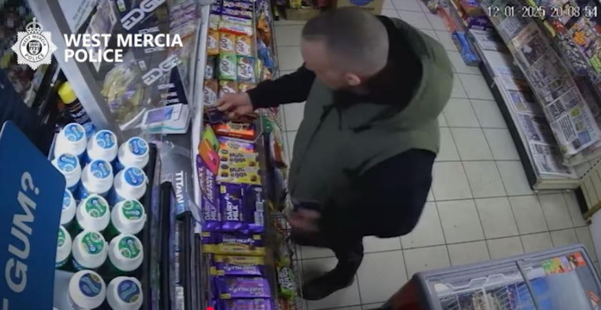 Surveillance footage of Matthew Jonathan selecting an item from a store shelf.