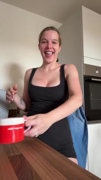 Helen Flanagan holding a red mug with a white rim and laughing.