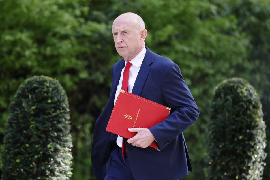 Britain's Secretary of State for Defence John Healey carries a red binder.