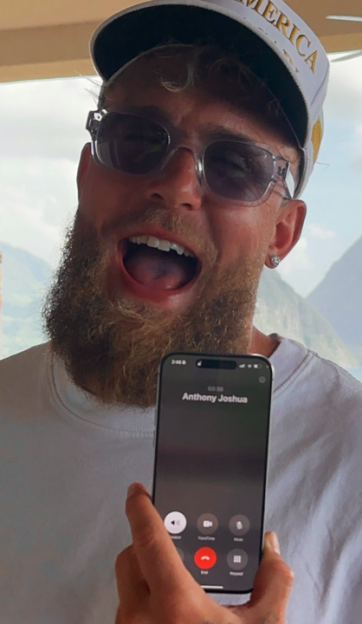 Jake Paul holding up a phone displaying an ongoing call with "Anthony Joshua".