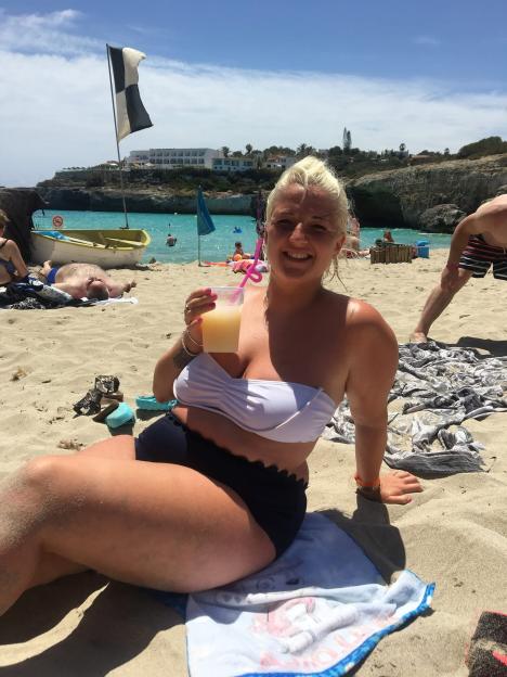 Marnie Dillon smiling on a beach, holding a drink, before she was sober.