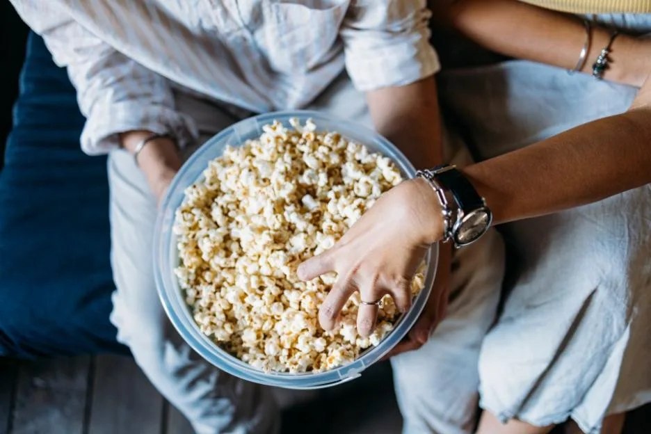 Two women sharing a large bowl of popcorn.