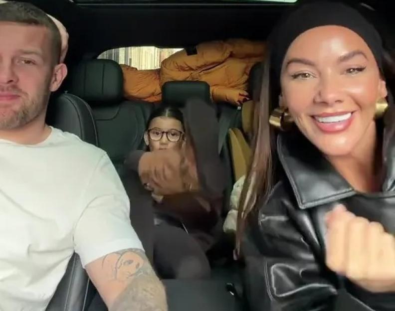 A man and a woman in the front seats of a car with a young girl sitting in the back.
