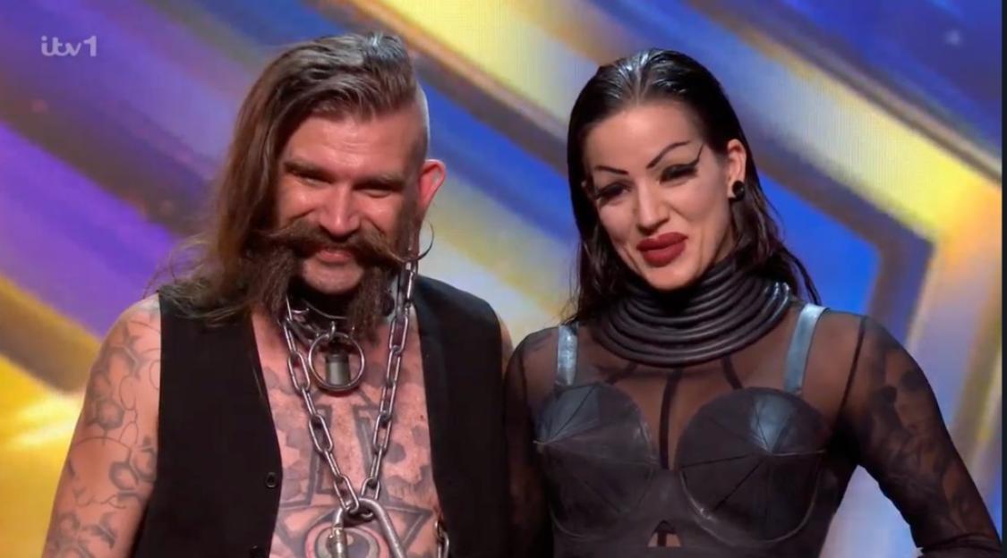 Two performers, a man and a woman, standing together on a stage.