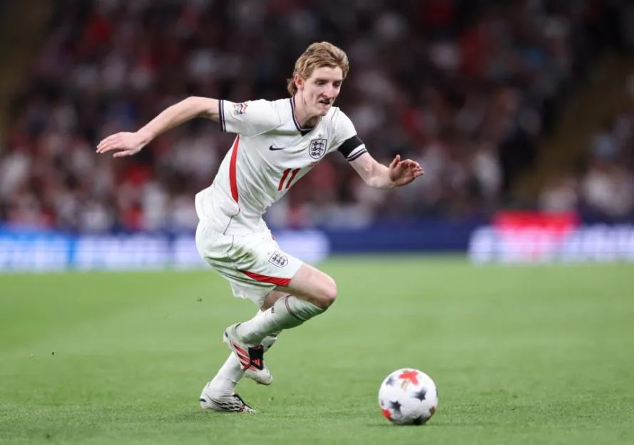 A male soccer player in a white uniform dribbles a soccer ball during a game between England and Spain.