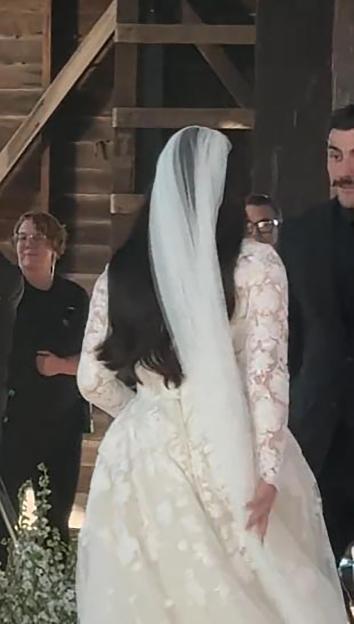 A runaway bride, seen from behind, walking away from the wedding while holding her dress.
