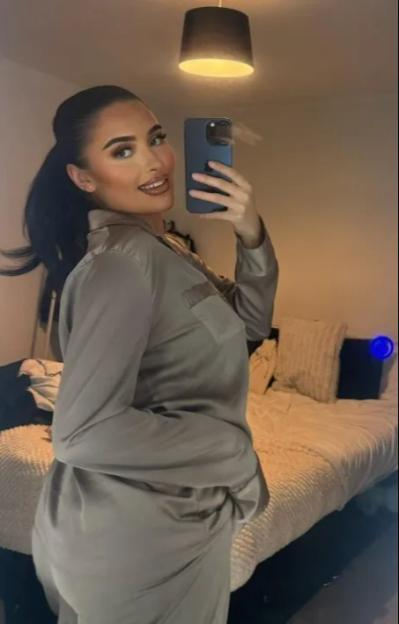 A woman in satin pajamas takes a mirror selfie.