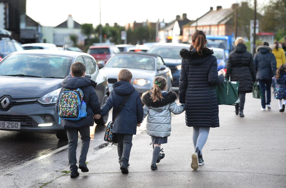 dated 17/01/20 of parents walking their children to school in Hornchurch, Essex, past stationary cars, as eight out of 10 people who responded to a survey about car idling said they want it banned outside school gates.