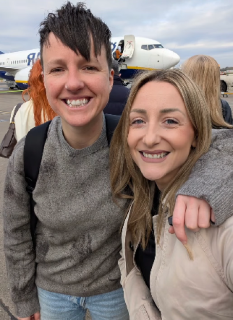 Two women smiling in front of a Ryanair airplane.