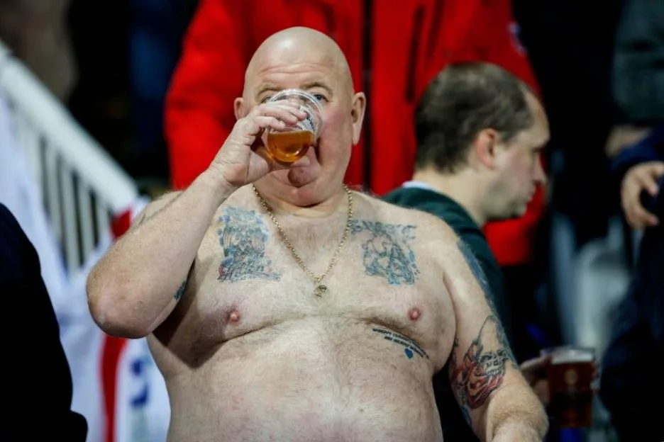 An England supporter drinking beer at a football match.