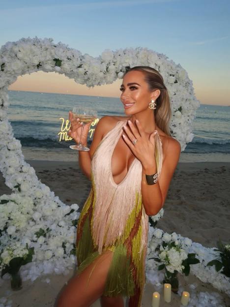 Amanda Harrington showing off her engagement ring on a beach.