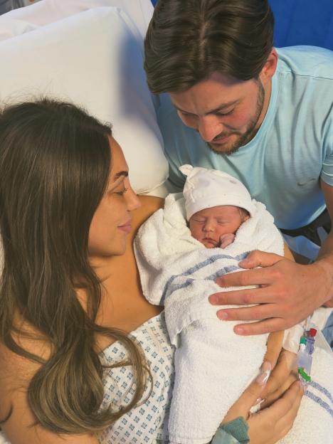 Sophie Kasaei holding her newborn baby, Brody, with Daryll Brook looking on.