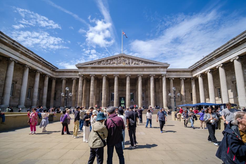 Panoramic view of the British Museum in London, with people gathered in front of its classical facade.