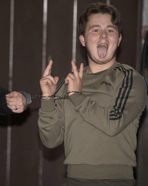 Albert Bowers, in handcuffs, sticks out his tongue and gives a "V" sign to the camera.