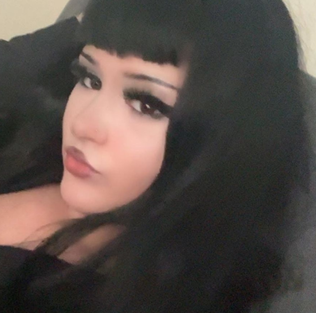 A young woman with black hair, bangs, dramatic eyeliner, and red lipstick.