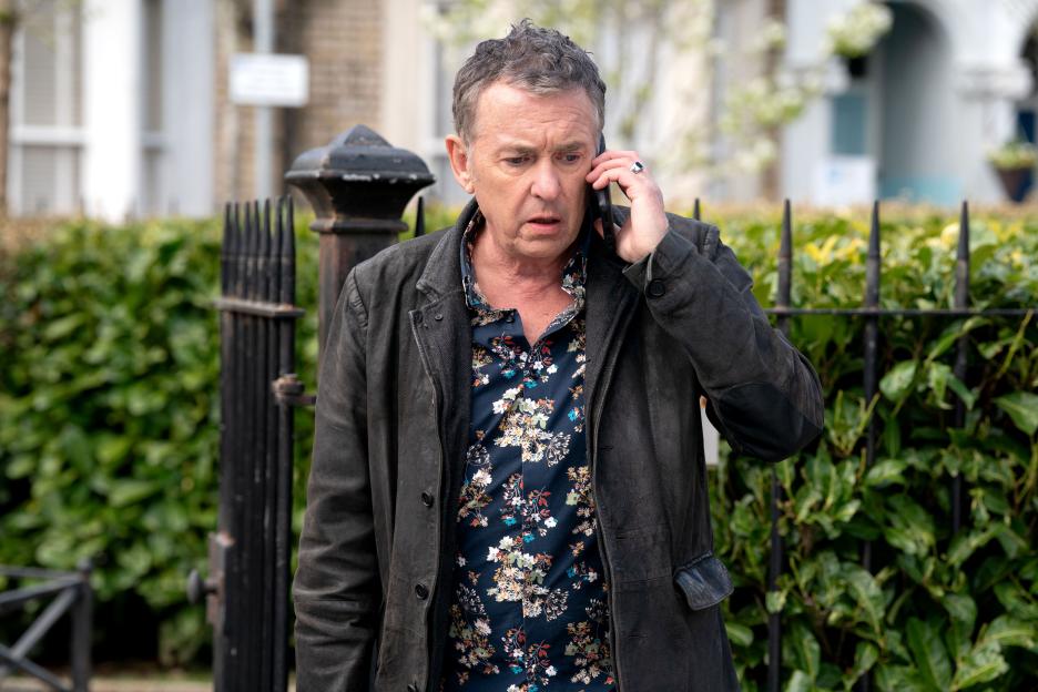Alfie Moon (Shane Richie) talks on the phone, looking worried, in EastEnders.