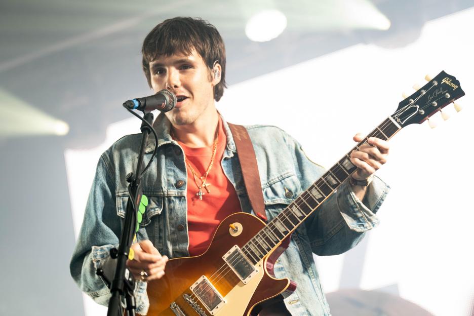 Cruz Beckham plays guitar and sings into a microphone at Reading Festival.