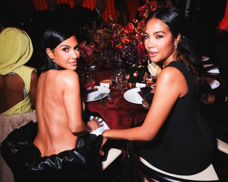 Kim Kardashian and another woman seated at a gala dinner table.