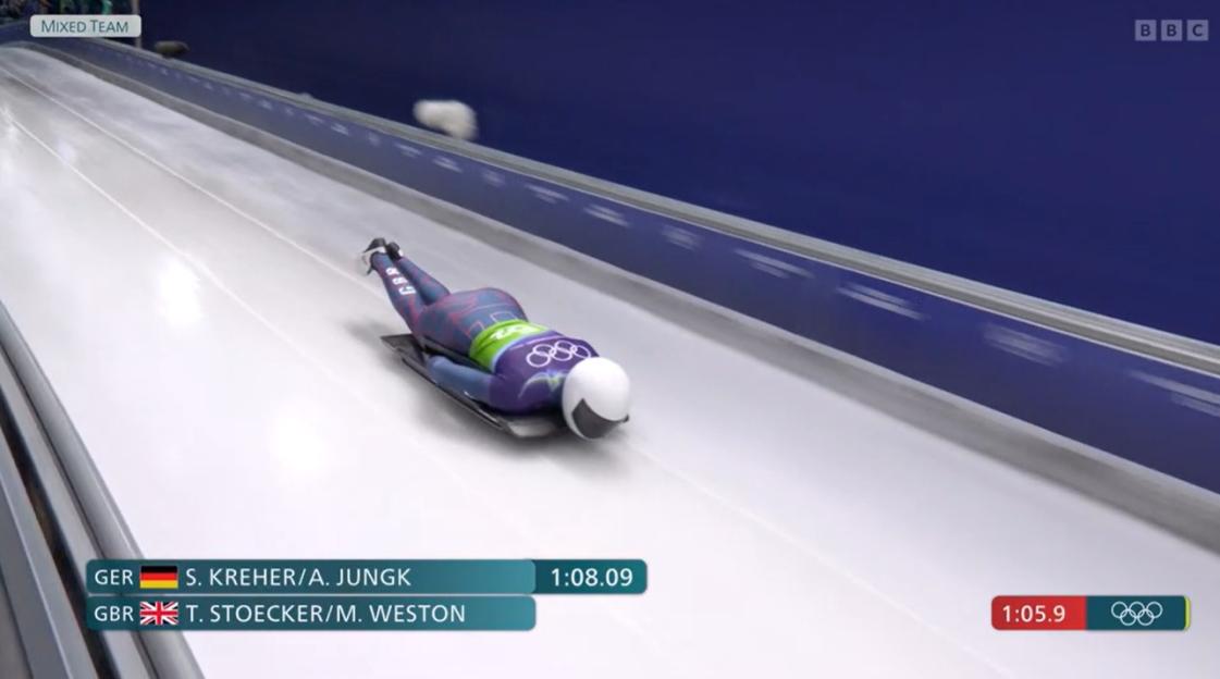 A person in a purple and green suit skeleton racing down an icy track with overlaid scores for Germany and Great Britain.