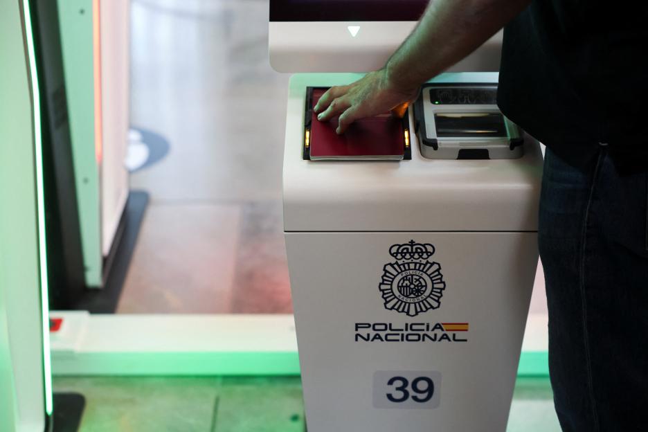 A person demonstrating the EU Entry/Exit System by placing a passport on a scanner.