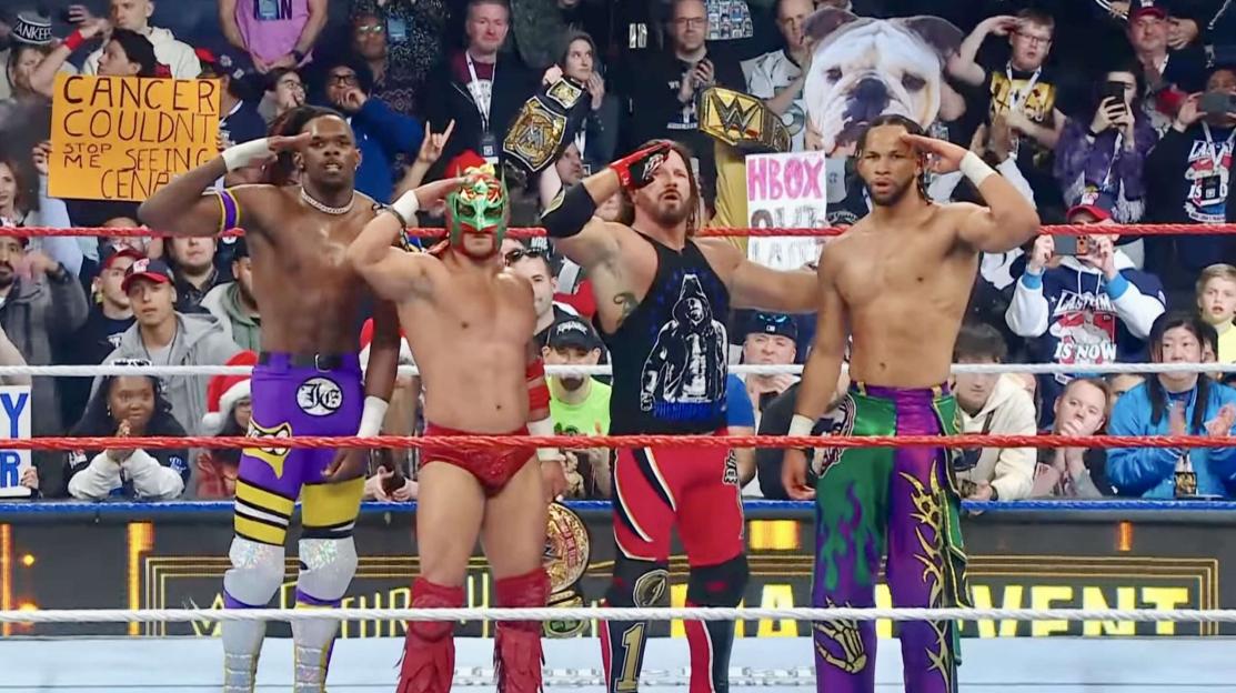 Jevon Evans, Leon Slater, AJ Styles, and Dragon Lee in a wrestling ring, saluting the crowd.