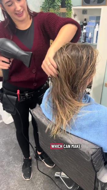 A hair stylist blow-drying a client's hair.