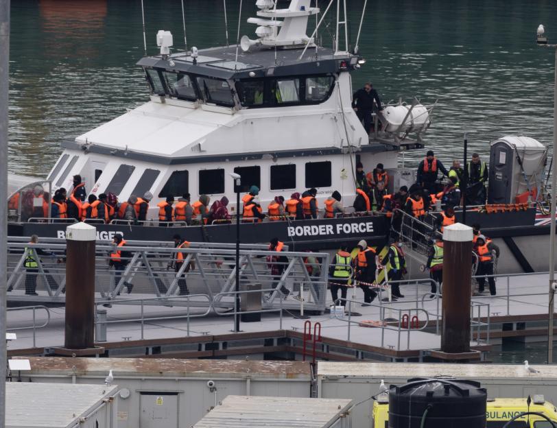 Migrants in orange life vests are helped off a Border Force vessel at Dover, Kent.