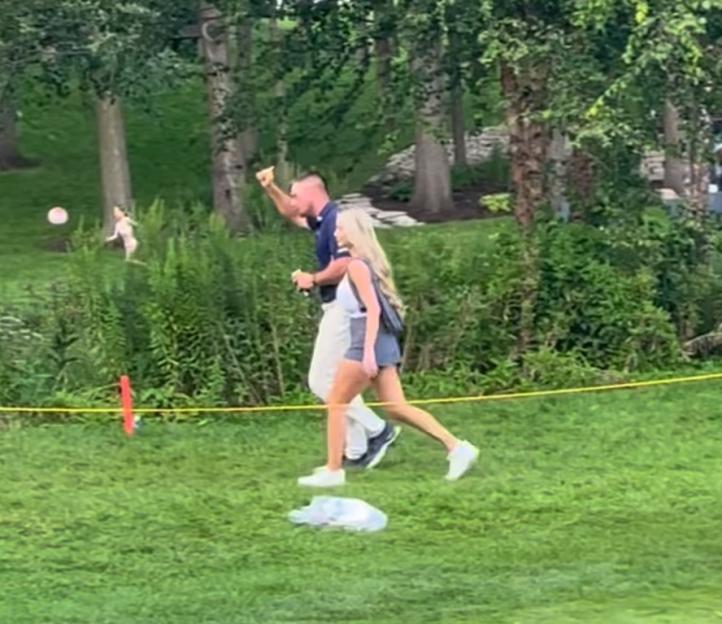 Bryson DeChambeau and girlfriend Lilia Schneider walking on a golf course.