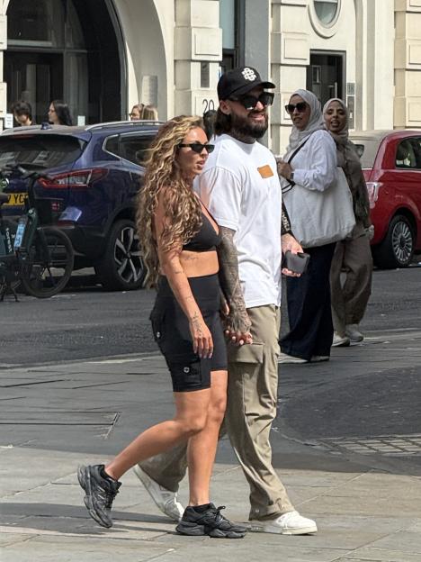 Jesy Nelson and Ben Davies holding hands while walking on a city street.