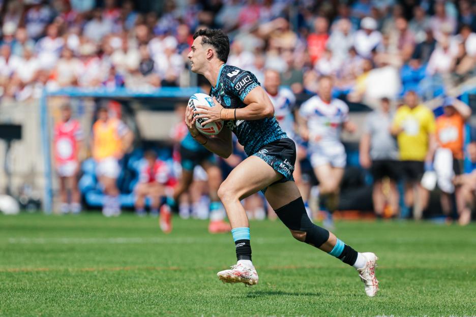Rugby player David Armstrong in a black and blue leopard-print jersey running with the ball.
