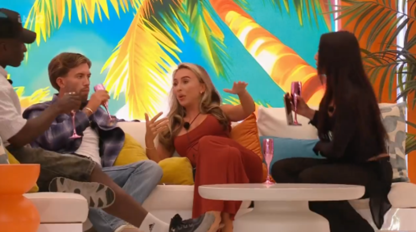 Four people sitting on a white sofa with brightly colored palm tree wallpaper in the background.