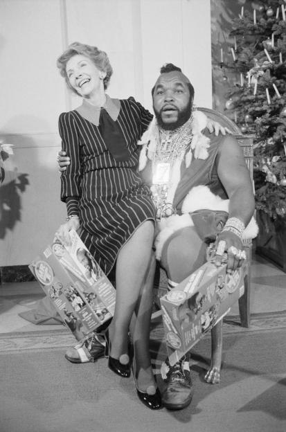 Nancy Reagan smiling, sitting on Mr. T's lap.