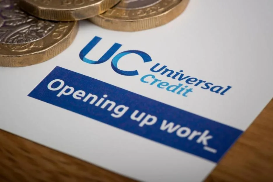 Universal Credit stationery and pound coins on a table.