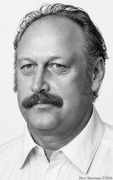 Black and white photo of a middle-aged man with a mustache and sideburns, looking directly at the camera.