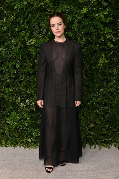 Claire Foy wearing a sheer black dress and black open-toe heels.